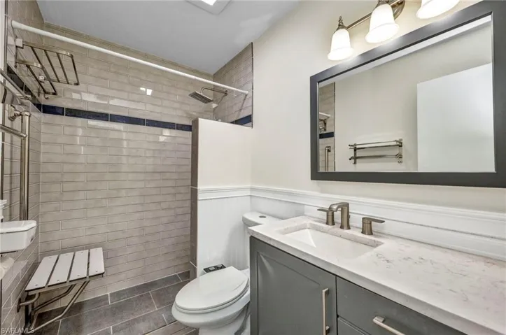 Fully tiled step-in shower with rain head shower and handheld want with shower seat and stainless shelving