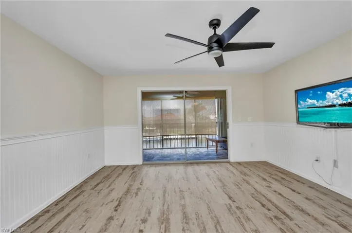 Empty room with luxury vinyl, canal front lanai, wainscoting, and ceiling fan