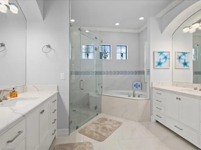 Bathroom with a shower stall, a garden tub, two vanities, recessed lighting, and ornamental molding