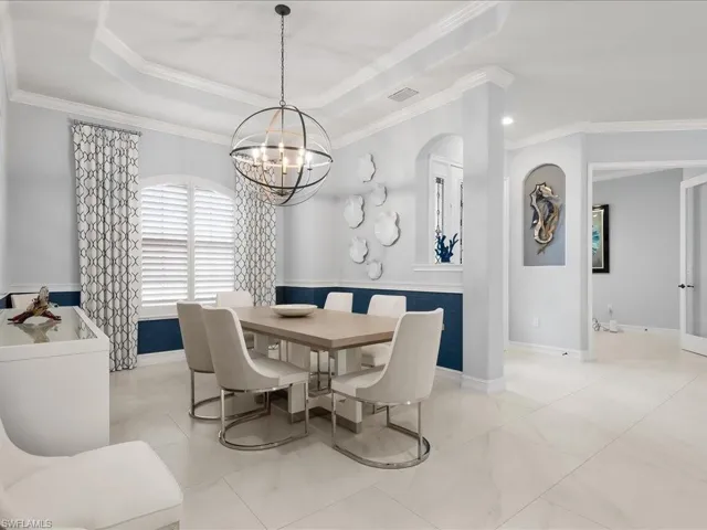 Dining area featuring ornamental molding, a chandelier, and a raised ceiling