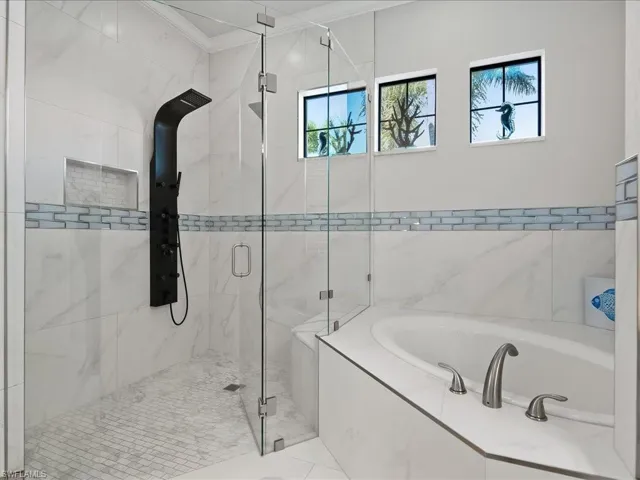 Bathroom featuring a bath, a marble finish shower, and ornamental molding