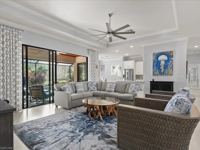 Living room featuring ornamental molding, ceiling fan, recessed lighting, tile patterned flooring, and a tray ceiling