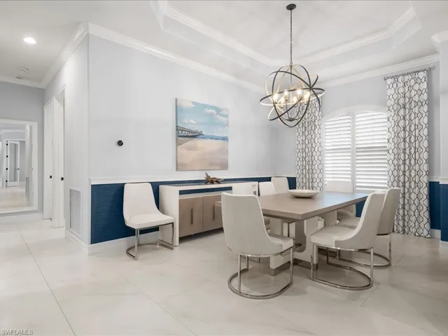 Dining space featuring crown molding, a tray ceiling, and a chandelier