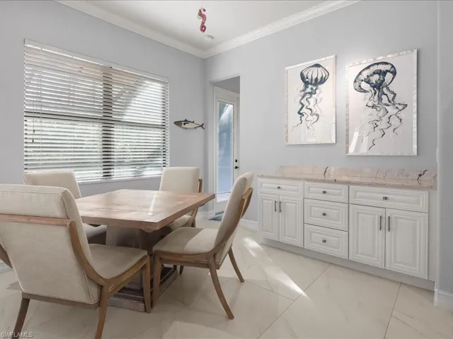 Dining space with crown molding and light marble finish flooring