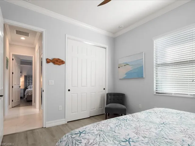 Bedroom featuring ornamental molding, light wood finished floors, a closet, and a ceiling fan