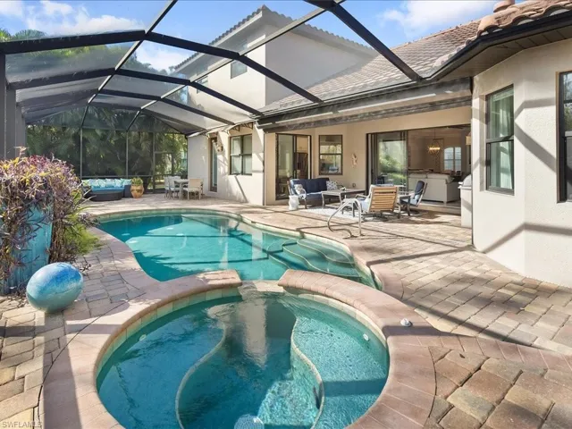 View of pool with a pool with connected hot tub, a patio area, a sunroom, a lanai, and outdoor lounge area
