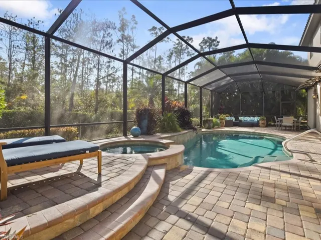 View of pool with a sunroom, glass enclosure, a pool with connected hot tub, and a patio
