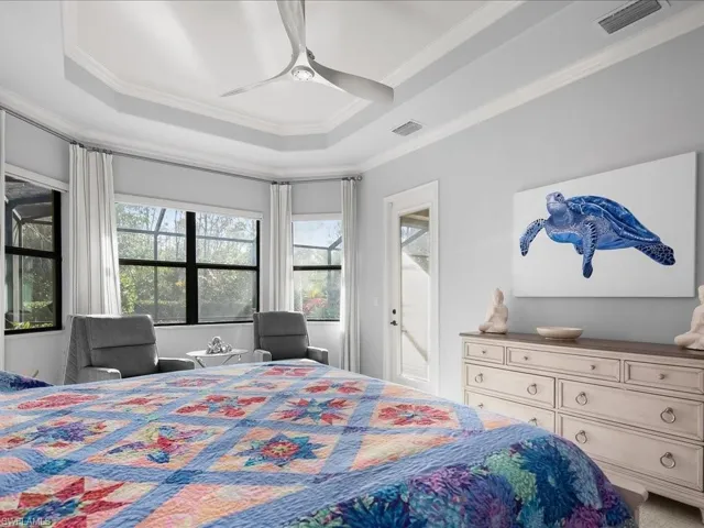 Bedroom with ceiling fan, a raised ceiling, and ornamental molding