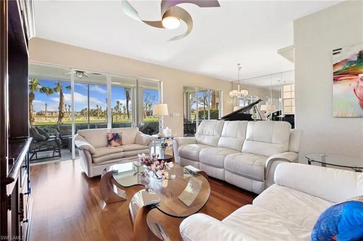 Living room with  wood-type flooring and ceiling fan with notable chandelier