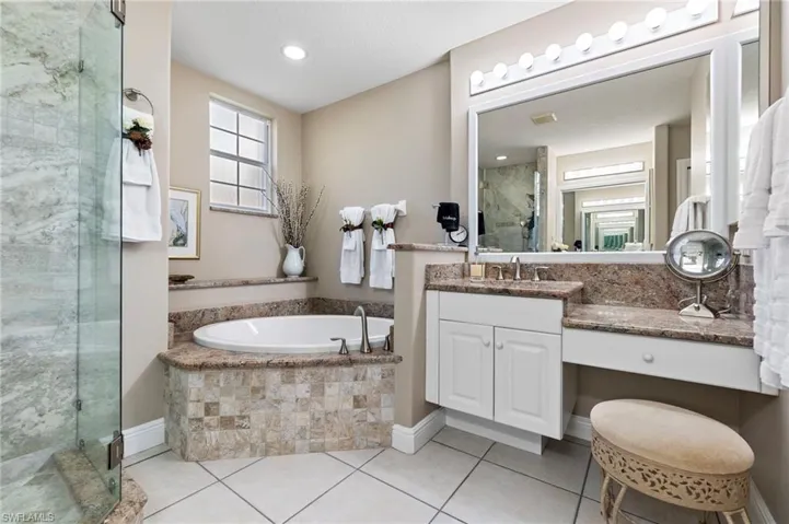 Bathroom featuring tile patterned floors, vanity, and plus walk in shower