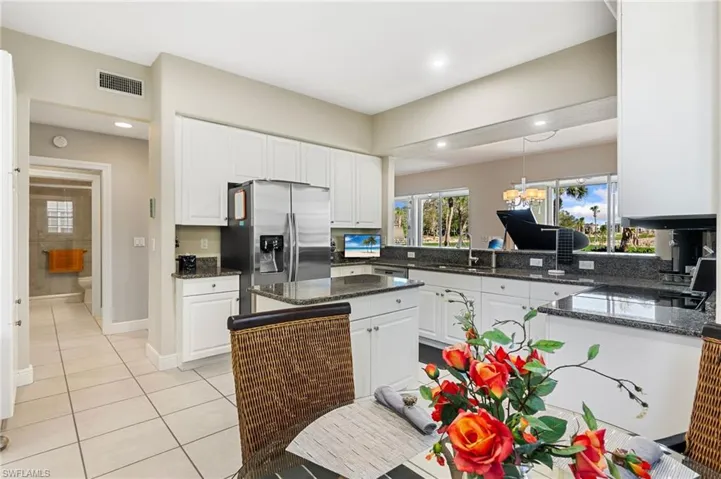 Kitchen with kitchen peninsula, white cabinetry, stainless steel appliances, and dark stone counters