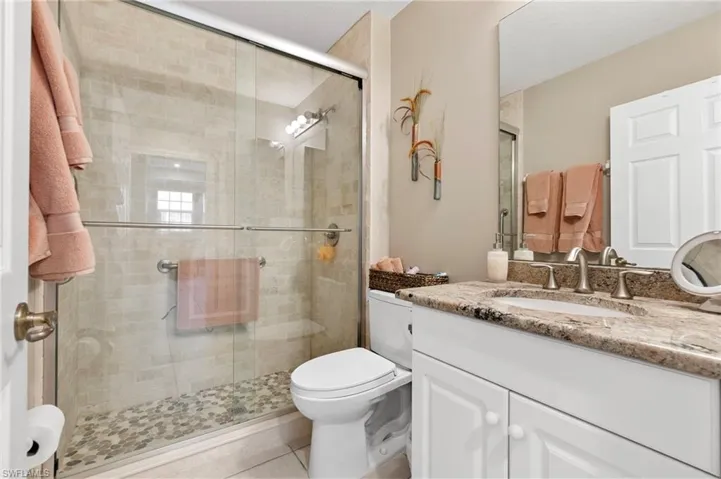 Bathroom featuring tile patterned floors, a shower with door, vanity, and toilet