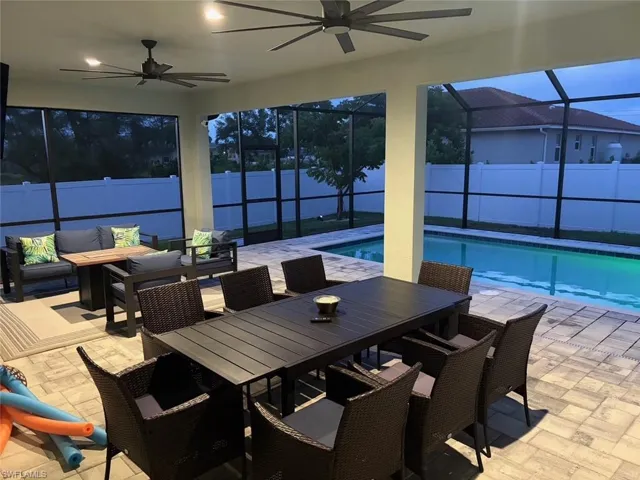 Fenced backyard featuring a sunroom, a patio area, glass enclosure, and a ceiling fan