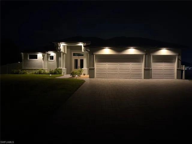 Prairie-style home with decorative driveway, a yard, stucco siding, a garage, and french doors