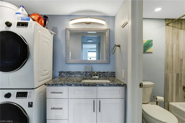 Washroom with sink and stacked washer / drying machine
