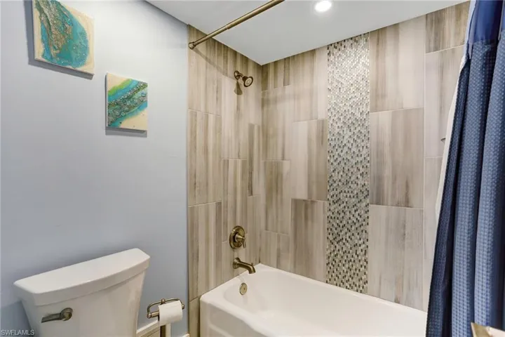 Bathroom featuring toilet and shower / bath combo with shower curtain