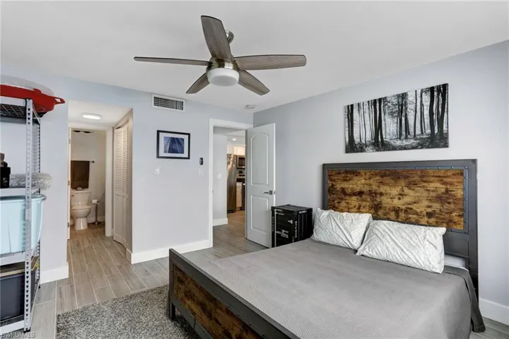 Bedroom with stainless steel refrigerator, ensuite bathroom, ceiling fan, and light hardwood / wood-style flooring