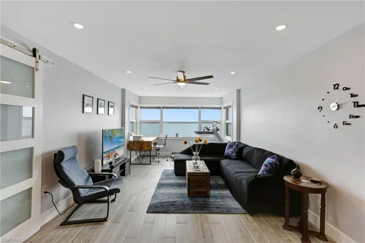 Living room featuring a barn door, ceiling fan, and light hardwood / wood-style floors