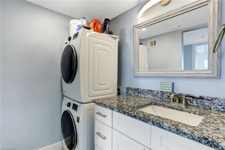 Washroom with sink and stacked washer / drying machine
