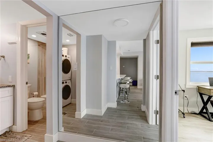 Bathroom with stacked washer and clothes dryer, vanity, toilet, and tile flooring