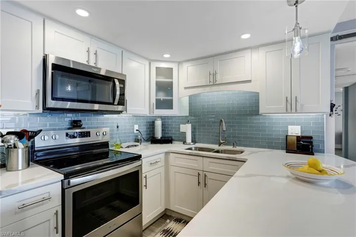 Kitchen featuring sink, stainless steel appliances, backsplash, and white cabinetry