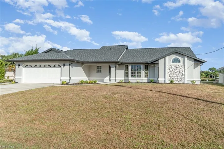 Single story home with a front lawn, stucco siding, concrete driveway, and an attached garage