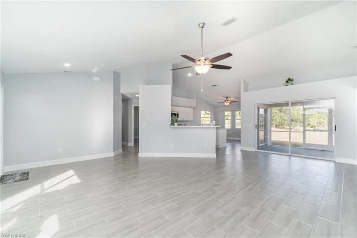 Unfurnished living room with ceiling fan, high vaulted ceiling, and wood finish floors