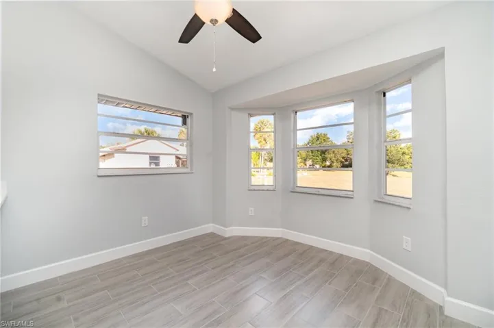 Spare room featuring vaulted ceiling, wood finish floors, and ceiling fan
