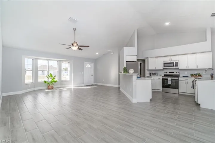Unfurnished living room featuring ceiling fan, wood tiled floors, recessed lighting, and high vaulted ceiling