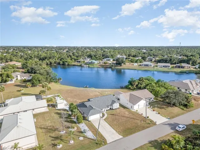 Aerial perspective of suburban area featuring a nearby body of water and a tree filled landscape