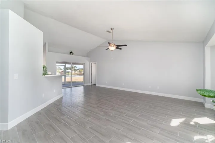 Unfurnished living room featuring vaulted ceiling, ceiling fan, and wood finish floors