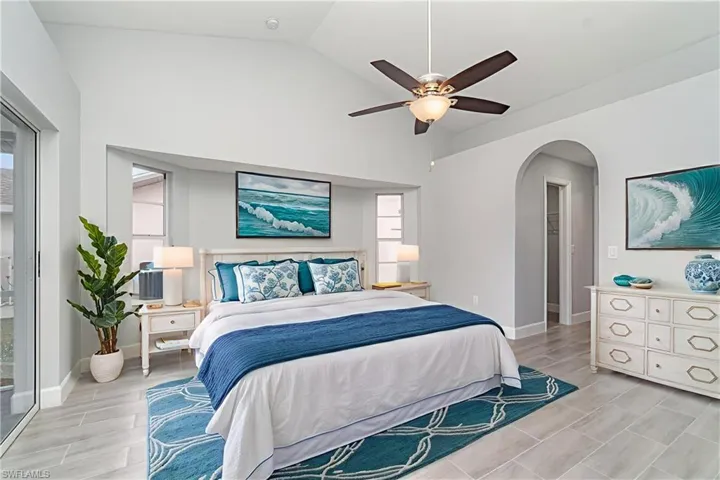 Bedroom with lofted ceiling, wood finish floors, access to outside, ceiling fan, and arched walkways