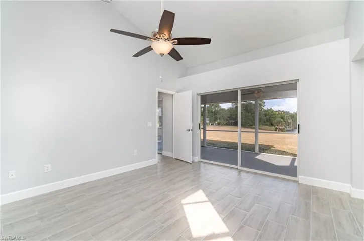 Empty room featuring vaulted ceiling, a ceiling fan, and wood tiled floors