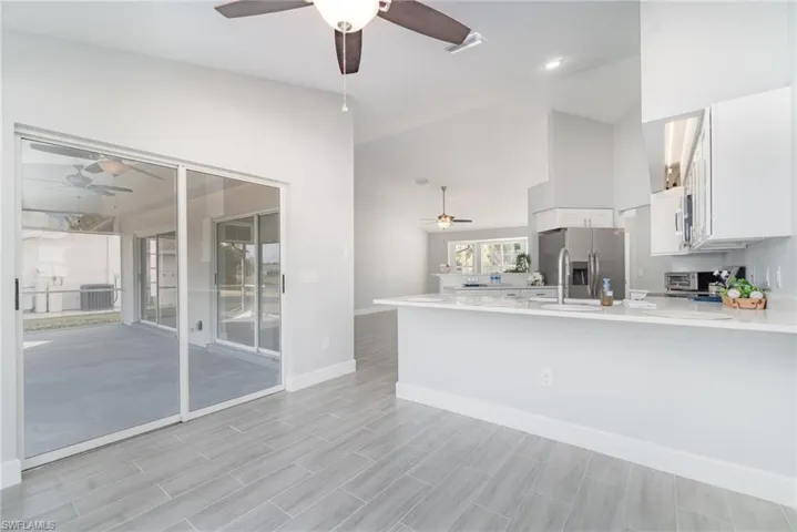 Unfurnished living room with wood tiled floors, a ceiling fan, and high vaulted ceiling