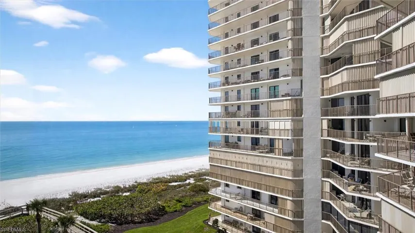High-rise coastal building featuring multiple private balconies with glass and metal railings