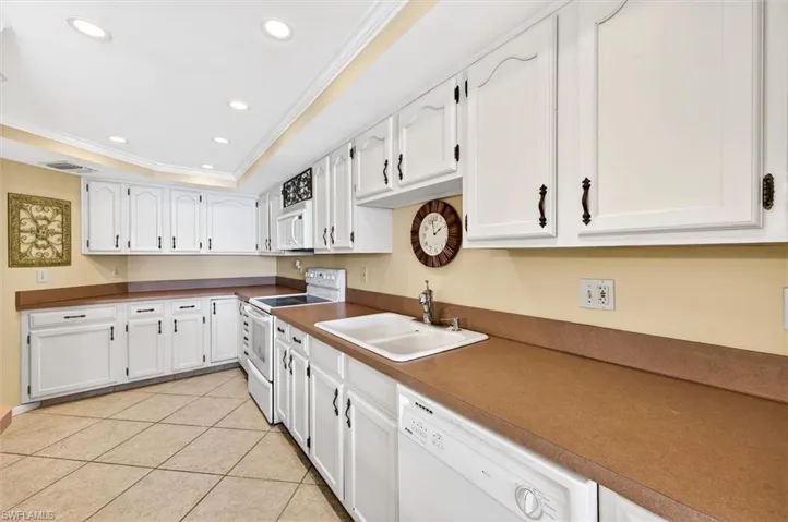 Kitchen featuring white cabinetry with dark hardware, solid surface countertops, and an integrated double basin sink