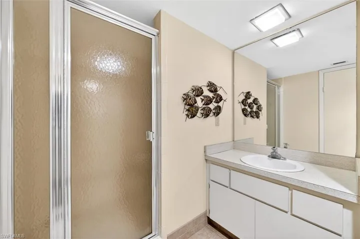 Bathroom featuring a built-in vanity with an integrated sink, a large wall-mounted mirror, and a shower enclosure with frosted glass and chrome framing