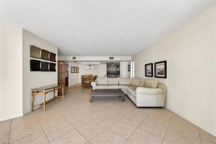 Open-concept living area featuring light-toned tile flooring, neutral wall finishes, a flat ceiling, and recessed lighting