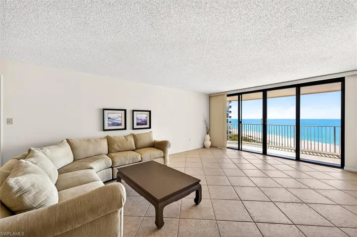 Spacious living area featuring large format tile flooring, a textured ceiling, and expansive sliding glass doors