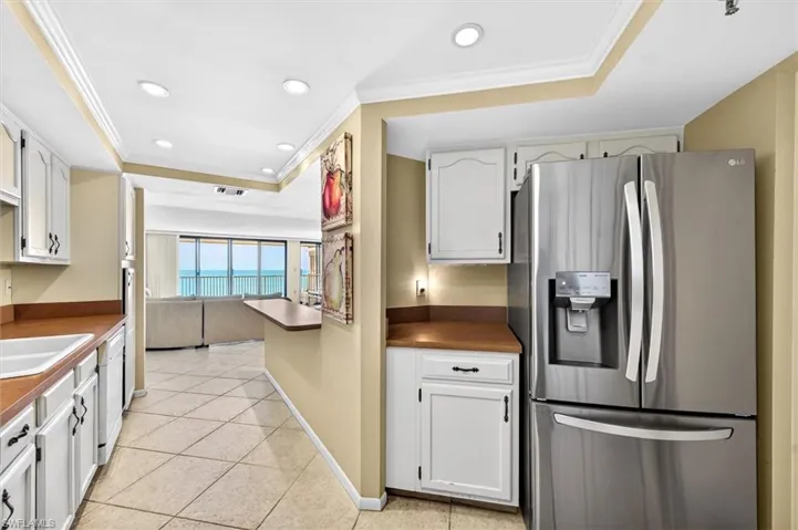 Galley kitchen featuring white cabinetry, wood-finish countertops, and tile flooring
