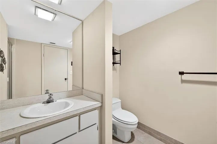 Bathroom featuring a vanity with a laminate countertop, integrated sink, and white cabinetry