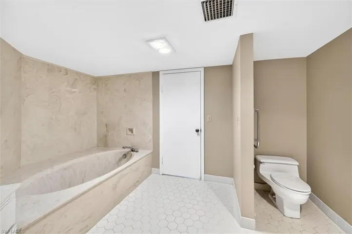 Soaking tub with integrated surround, complemented by white hexagonal floor tiling