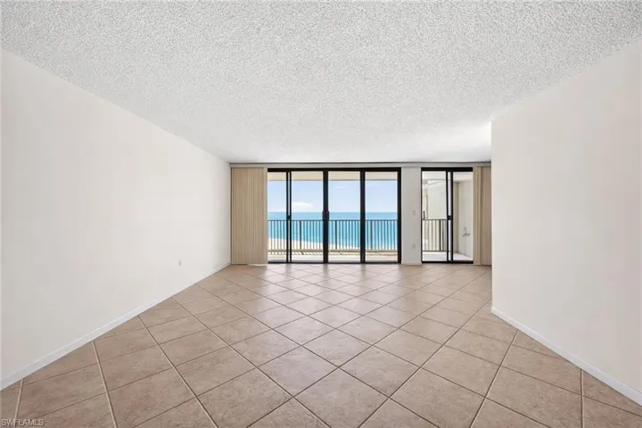 Expansive interior space featuring large format square tile flooring and a textured ceiling