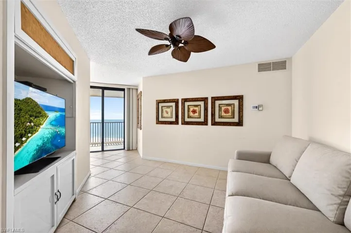 Sliding glass doors open to a balcony featuring a metal railing and expansive ocean scenery