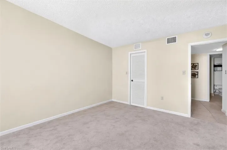 Carpeted room featuring neutral wall tones, white baseboards, and a textured ceiling