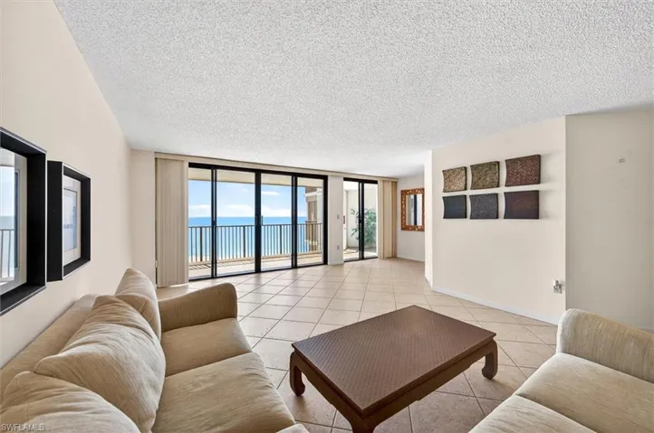 Spacious living area featuring large sliding glass doors opening to a private balcony with water frontage