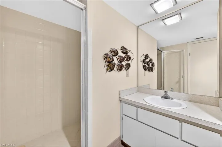 Bathroom featuring a vanity with an integrated sink, a large wall-mounted mirror, and a tiled shower with a sliding glass door