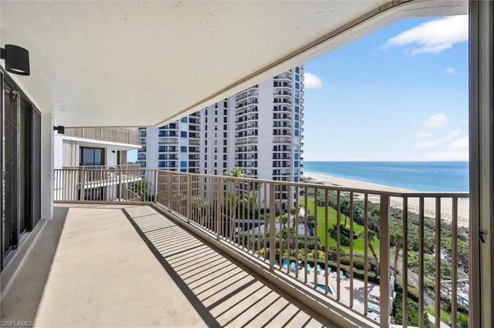 Expansive balcony with concrete flooring, a bronze metal railing, and a wall-mounted light fixture