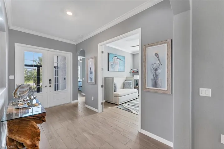 Foyer entrance featuring light hardwood / wood-style flooring, ornamental molding, and french doors