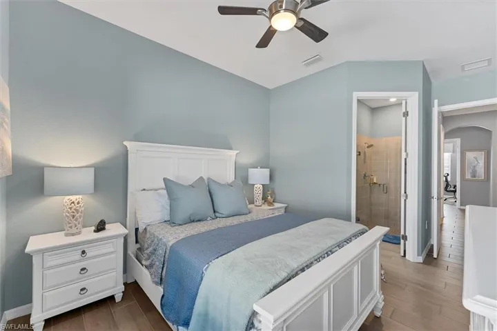 Bedroom featuring ceiling fan, connected bathroom, and dark hardwood / wood-style floors